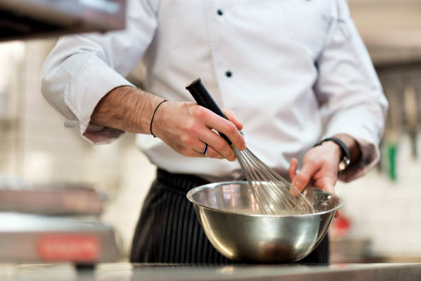 istock Chef in hotel or restaurant kitchen cooking, only hands. He is whisking ingredients. 866879222