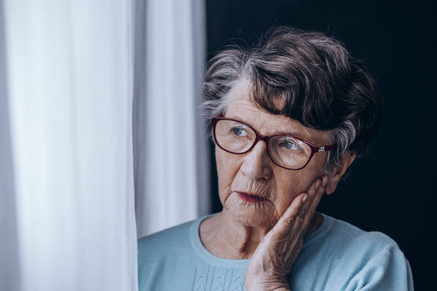 istock Elderly woman looking through window 866882640