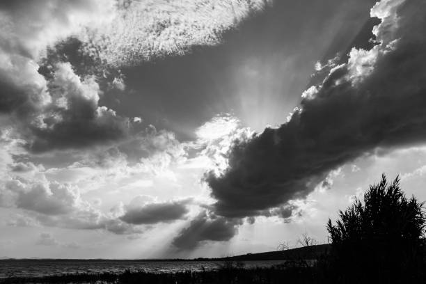 istock Powerful sun rays coming out through some clouds above a lake shore 866886020