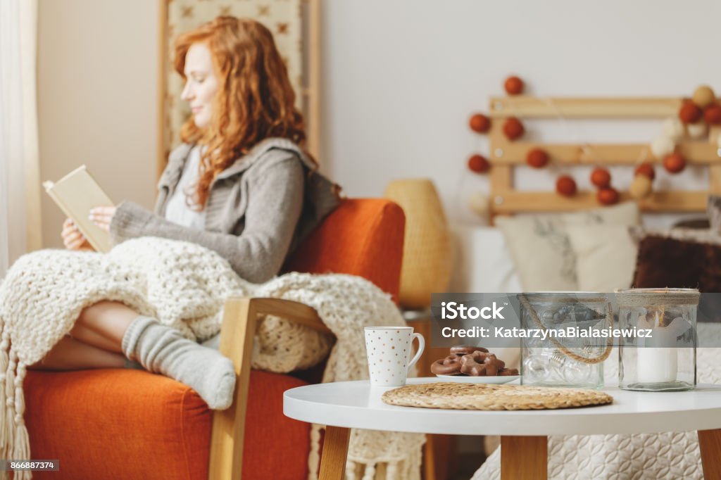 Table with gingerbread and tea Small table with gingerbread and a tea along with a candle and a young lady reading a book in the background Autumn Stock Photo