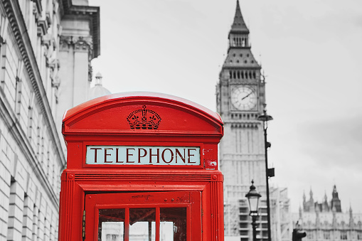 A traditional red phone booth in London with the Big Ben in a black and white background, England, the UK.