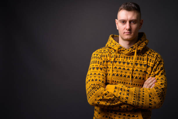 istock Young handsome man wearing yellow hoodie against gray background 866897708