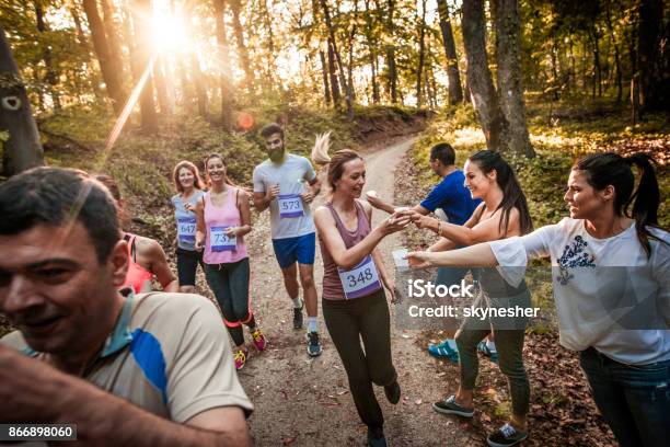 Volunteers Passing Fresh Water To Marathon Runners During The Race In Nature Stock Photo - Download Image Now