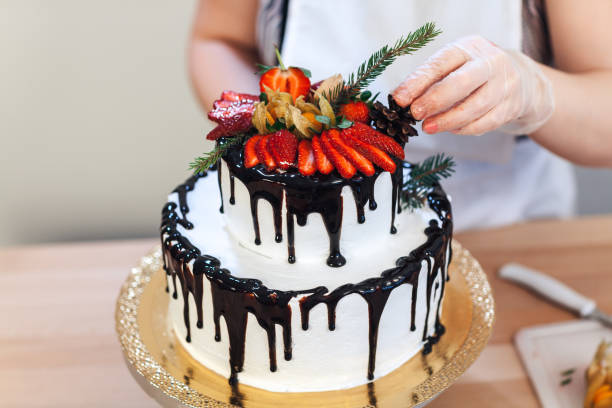 istock Female hand decorates a white cream cake with fruit, close-up 866901734