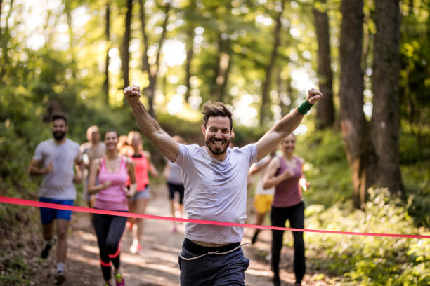 maratonista feliz ganar y cruzar la línea de meta con los brazos alzados. - finish line fotografías e imágenes de stock