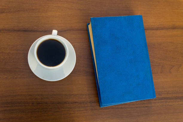 istock Cup of coffee and closed book on wooden table 866904408