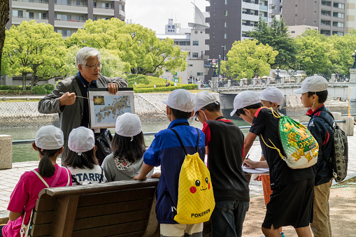 Hiroshima, Japan - May 25, 2017: Volunteer teacher is telling a group of  students about the history of the A bomb in the Hiroshima Peace Memorial Park