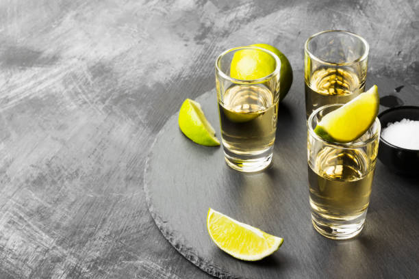 tequila mit kalk und salz auf einem dunklen hintergrund. kopieren sie raum. essen-hintergrund - tequila slammer stock-fotos und bilder