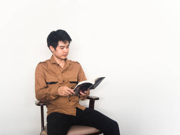 istock asia man is reading a book on a chair on white background 866920304