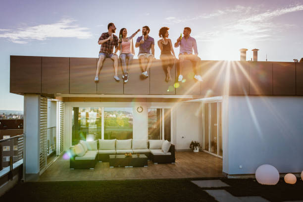 istock Group of young cheerful people talking while sitting on a penthouse rooftop. 866920504