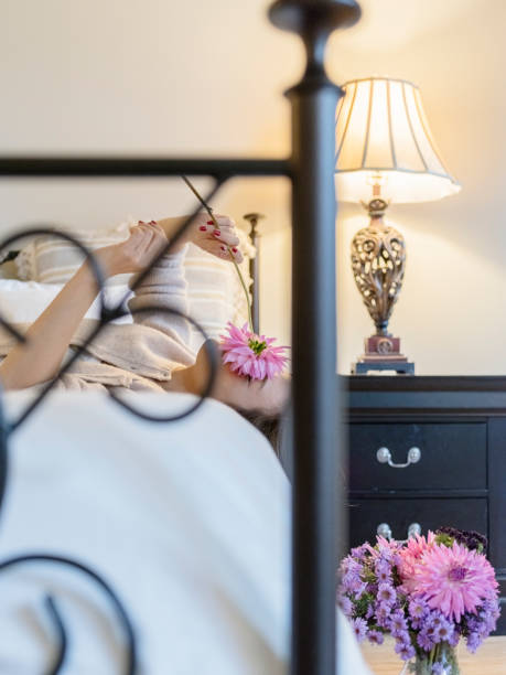 attractive woman lying on bead with bouquet.