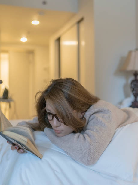 istock japanese woman lying on bed reading a book 866921562