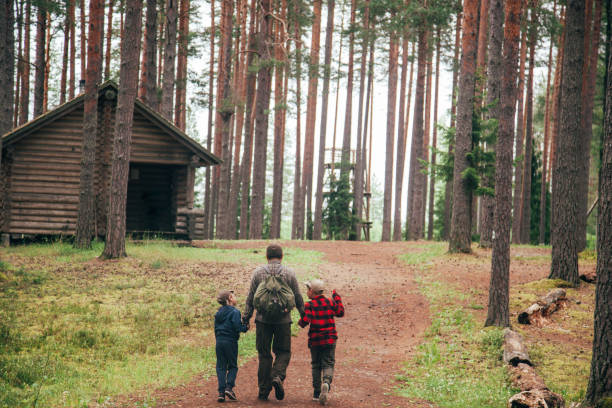 Father with his two sons going to log cabin