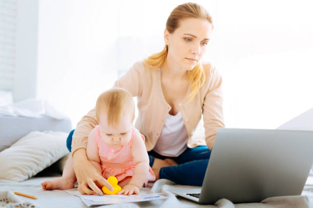 istock Tired young mother working at her laptop 866926312