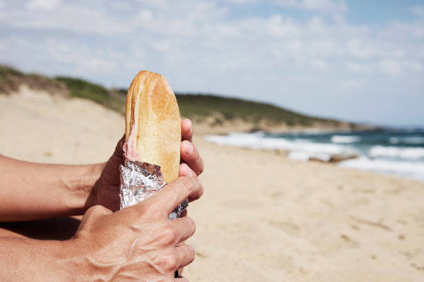 istock young man eating a sandwich on the beach 866936198