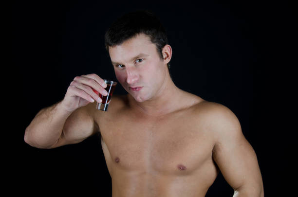 istock The man drinks alcohol. Attractive guy without a shirt. 866936648