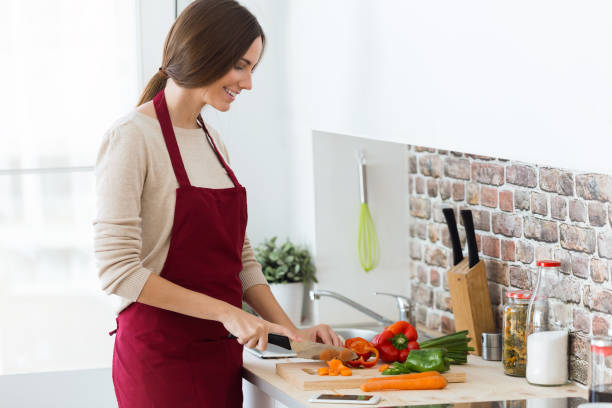 istock Beautiful young woman cutting fresh vegetables in the kitchen. 866939448