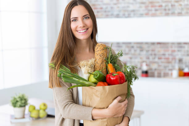 bella giovane donna con verdure in borsa da spesa a casa. - paper bag groceries food vegetable foto e immagini stock