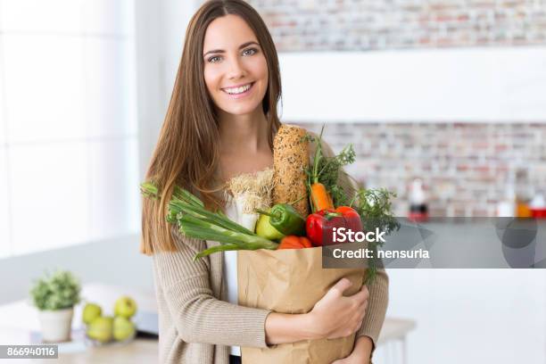 Beautiful Young Woman With Vegetables In Grocery Bag At Home Stock Photo - Download Image Now