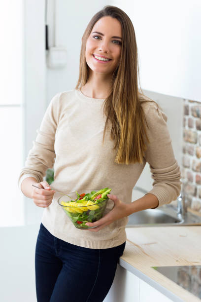 istock Beautiful young woman eating fruit salad in the kitchen. 866940198