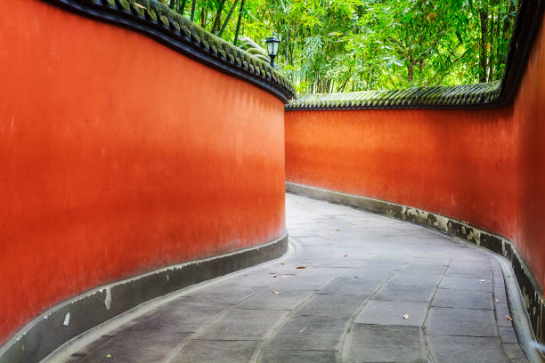 istock Curvy red walls passage surrounded by bamboo forest. 866944534
