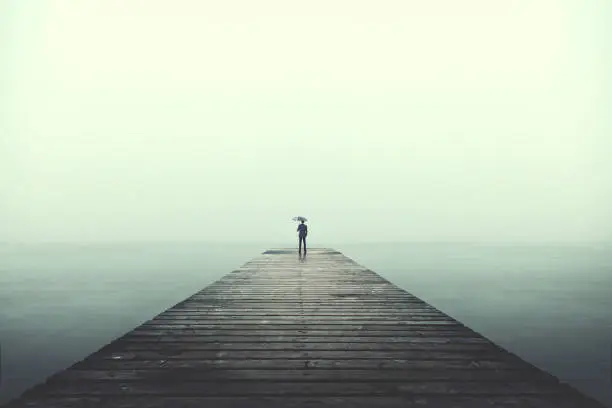 Sad business man with umbrella looking at the horizon