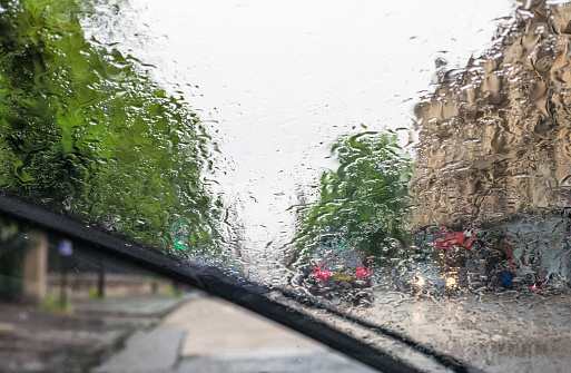 A windscreen wiper clearing the screen of rain on a British city street.