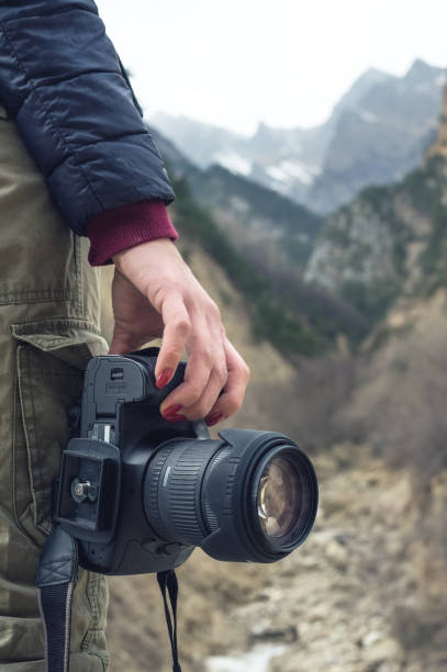 istock A female hand holds a camera against a mountain landscape 866954230