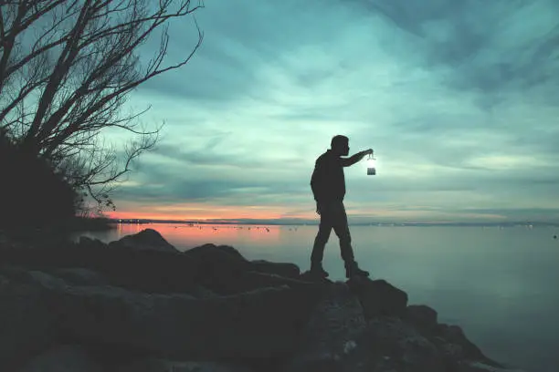 Photo of Man with torch walking on rocks at lake in night