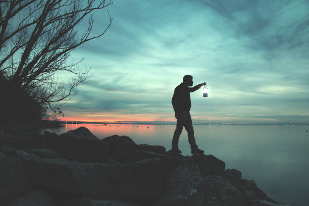 человек с факелом, гуляя по скалам у озера ночью - the rocks flash стоковые фото и изображения