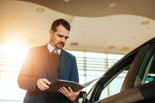 istock Car dealer looking at notepad in car salon. 866955164