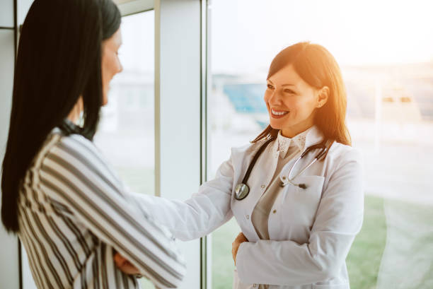 cheerful woman doctor talking with young woman in office. - friendly match imagens e fotografias de stock