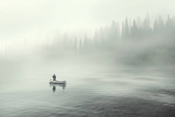 hombre pescando en un barco en un lago de niebla mística - mistic fotografías e imágenes de stock