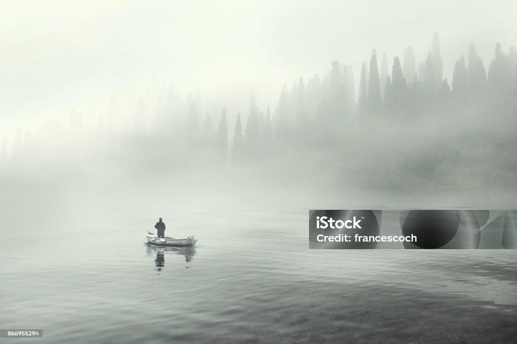 Man fishing on a boat in a mistic foggy lake Fog Stock Photo