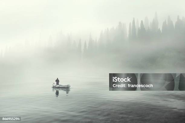 Man Fishing On A Boat In A Mistic Foggy Lake Stock Photo - Download Image Now - Fog, Lake, Fishing