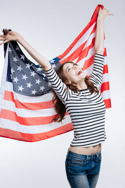 istock Slim cheerful woman lifting up US flag behind her back 866959320