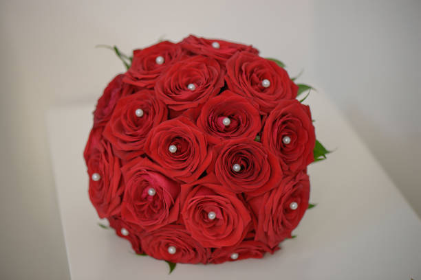 istock Sophisticated round wedding bouquet with red roses and pearl drops positioned on a white minimalist table 866962736