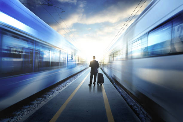 uomo d'affari tra due treni alla stazione ferroviaria - railroad track direction choice transportation foto e immagini stock