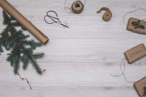 istock Christmas creative process composition. Presents with empty tag and decor of fir-tree branches, rope, craft paper and pine cones, scissors. Holiday composition on whooden background. Top view 866981832