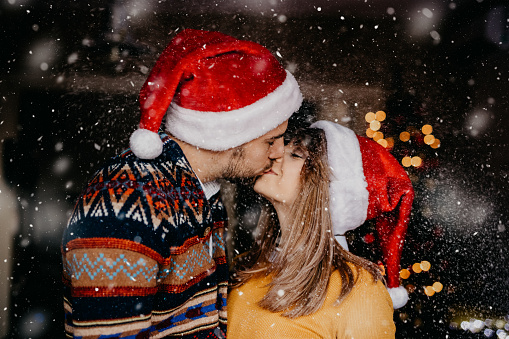 a loving couple kissing outside while snow falls