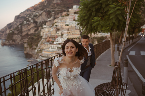 Photo of a just married couple running through the small streets of Positano, Italy