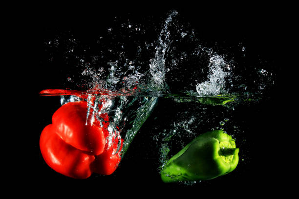 istock Red and green peppers falling into water 867015192