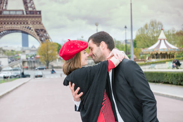 young romantic couple kissing near the eiffel tower - paris france eiffel tower love kissing imagens e fotografias de stock