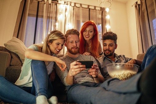 A group of young friends watching a movie on a mobile phone.