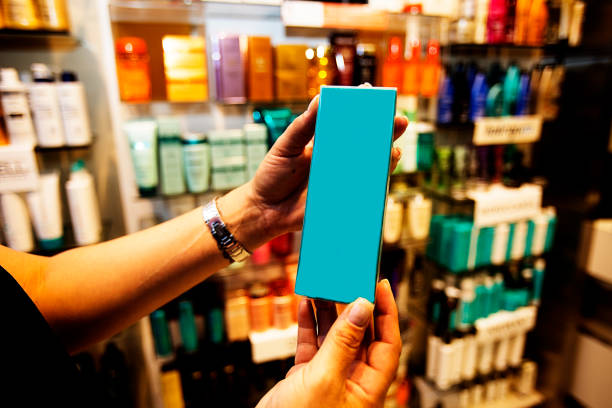 Womans hands hold a blue box in a cosmetic store aisle while shopping