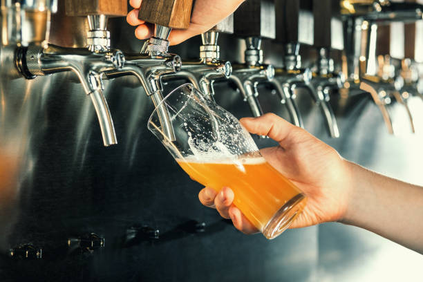 Hand of bartender pouring a large lager beer in tap Hand of bartender pouring a large lager beer in tap. Soft, vintage instagram effect on photo beer pump stock pictures, royalty-free photos & images