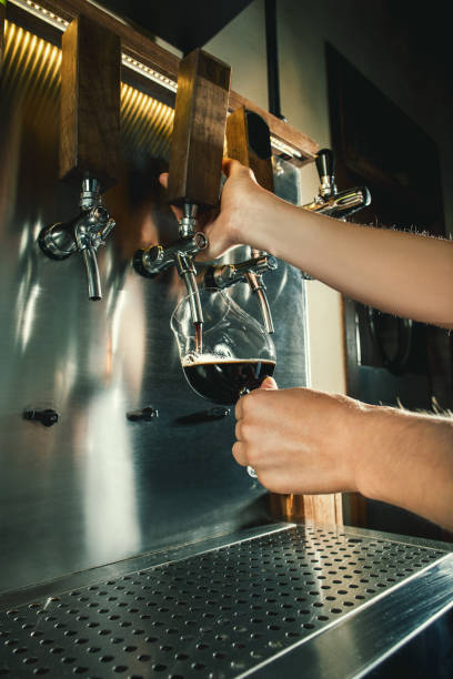 istock Hand of bartender pouring a large lager beer in tap 867023728
