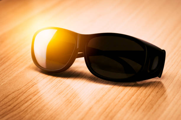 black sunglasses on wood table with summer sun light UV protection