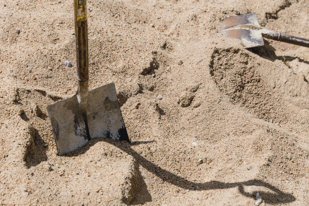 Shovel placed on sand for construction in sunny day with strong shadow