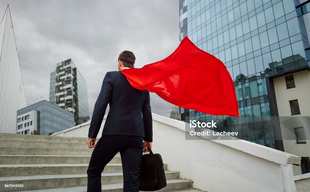 A superhero businessman climbs the stairs to business buildings A superhero businessman climbs the stairs to business buildings. Superhero Stock Photo